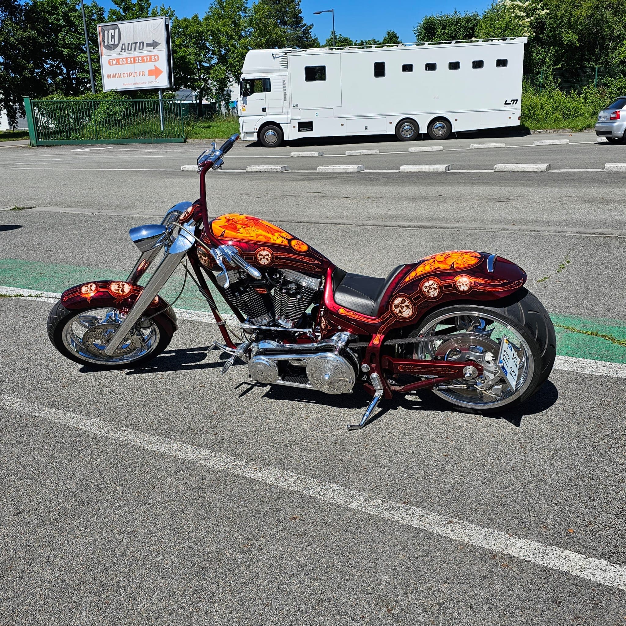 Chopper custom flammes orangées sur le parking du centre